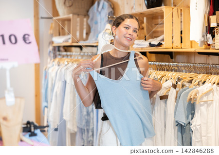Young woman choosing T-shirt in clothing store Young woman choosing T-shirt in clothing store 142846288