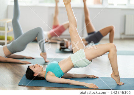 Group of young women doing pilates exercises Group of young women doing pilates exercises 142846305