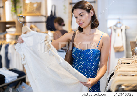 Young woman choosing clothes in a store in summer Young woman choosing clothes in a store in summer 142846323