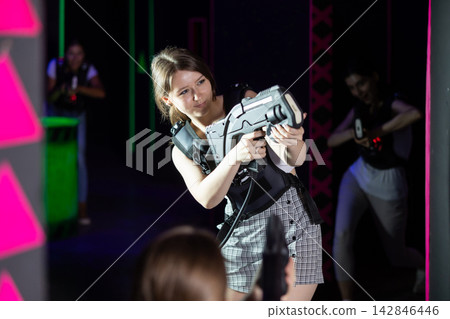Young lady having fun playing lasertag in labyrinth 142846446