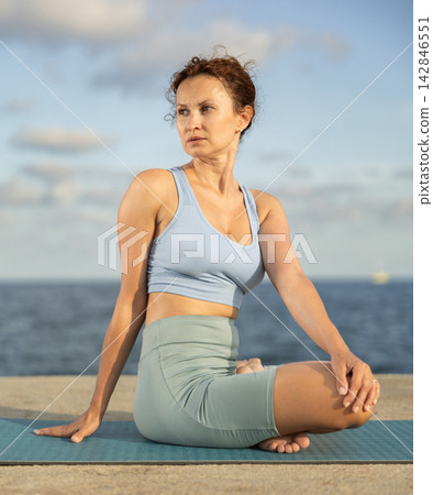 Woman performing Ardha Matsyendrasana position yoga training Woman performing Ardha Matsyendrasana position yoga training 142846551