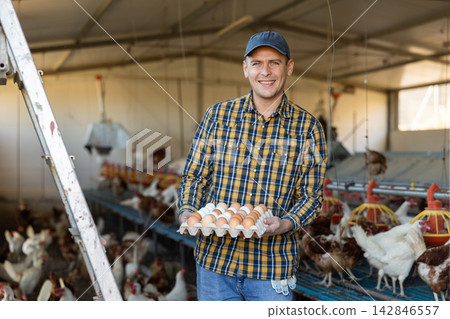 Portrait of man farmer holding eggs in hands in henhouse Portrait of man farmer holding eggs in hands in henhouse 142846557