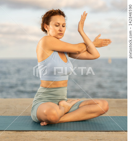 Ardha Matsyendrasana yoga pose - woman doing yoga On beach Ardha Matsyendrasana yoga pose - woman doing yoga On beach 142846590