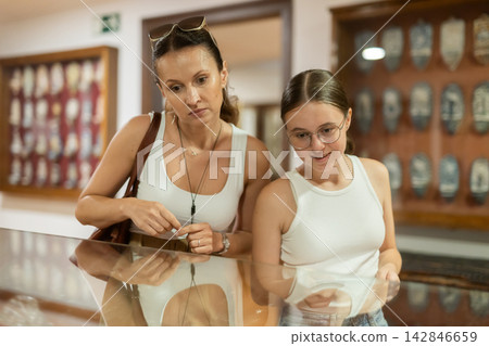 Woman and teenage girl looking at exhibit in museum display Woman and teenage girl looking at exhibit in museum display 142846659