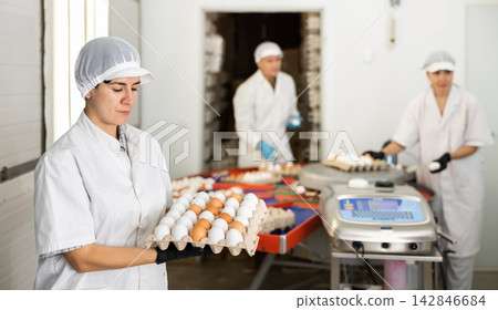 Hispanic female worker of poultry farm holding cardboard tray with eggs 142846684