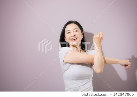 一位身穿普拉提和瑜珈服的女士伸展雙臂;一位中年日本女性伸展身體以放鬆身心。 一位身穿普拉提和瑜珈服的女士伸展雙臂;一位中年日本女性伸展身體以放鬆身心。 142847060