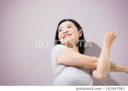 一位身穿普拉提和瑜珈服的女士伸展雙臂;一位中年日本女性伸展身體以放鬆身心。 一位身穿普拉提和瑜珈服的女士伸展雙臂;一位中年日本女性伸展身體以放鬆身心。 142847061