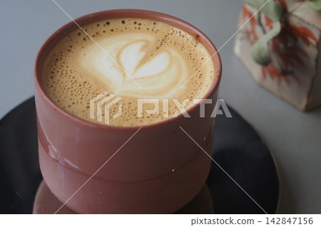 Coffee served in a pink cup with heart design on top of the foam Coffee served in a pink cup with heart design on top of the foam 142847156