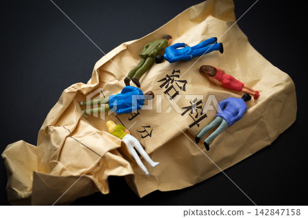 皺巴巴的工資信封和倒在黑色背景上的人們。 皺巴巴的工資信封和倒在黑色背景上的人們。 142847158