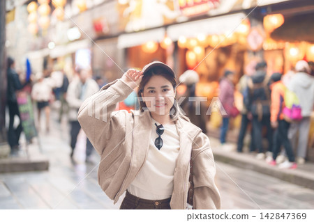 Happy woman traveler travel in Chengdu city. Tourist sightseeing and shopping in Jinli Ancient Street. Famous Landmark for tourism attraction in Sichuan, China Happy woman traveler travel in Chengdu city. Tourist sightseeing and shopping in Jinli Ancient Street. Famous Landmark for tourism attraction in Sichuan, China 142847369