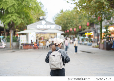 Happy woman traveler travel in Dujiangyan city. Tourist sightseeing Guanxian Ancient City near Chengdu. Landmark and popular for tourism attraction in Sichuan, China Happy woman traveler travel in Dujiangyan city. Tourist sightseeing Guanxian Ancient City near Chengdu. Landmark and popular for tourism attraction in Sichuan, China 142847396