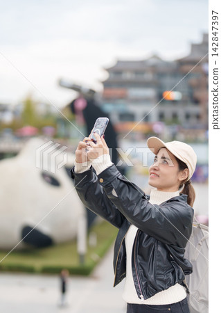 Happy woman traveler travel in Dujiangyan city. Tourist sightseeing Yangtianwo Square and Guanxian Ancient City near Chengdu. Landmark and popular for tourism attraction in Sichuan, China Happy woman traveler travel in Dujiangyan city. Tourist sightseeing Yangtianwo Square and Guanxian Ancient City near Chengdu. Landmark and popular for tourism attraction in Sichuan, China 142847397