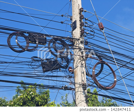 Messy Telecommunication Wires and Fiber Optic Cable Loops on Concrete Utility Pole Against Blue Sky Messy Telecommunication Wires and Fiber Optic Cable Loops on Concrete Utility Pole Against Blue Sky 142847411