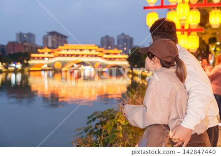 Happy couple traveler travel in Chengdu city. Tourist sightseeing Beautiful Anshun Bridge at night. Famous Landmark for tourism attraction in Sichuan, China Happy couple traveler travel in Chengdu city. Tourist sightseeing Beautiful Anshun Bridge at night. Famous Landmark for tourism attraction in Sichuan, China 142847440