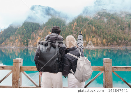 Happy Couple traveler travel in jiuzhaigou national park in Sichuan, China. Tourist sightseeing beautiful lake and snow mountain in Autumn season. Famous Landmark and Vacation near Chengdu, China Happy Couple traveler travel in jiuzhaigou national park in Sichuan, China. Tourist sightseeing beautiful lake and snow mountain in Autumn season. Famous Landmark and Vacation near Chengdu, China 142847441