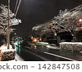 A snow-covered winter night road and street trees 142847508
