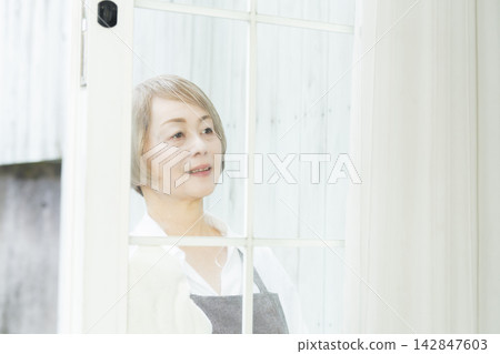 A senior woman wiping down surfaces in the living room. A senior woman wiping down surfaces in the living room. 142847603