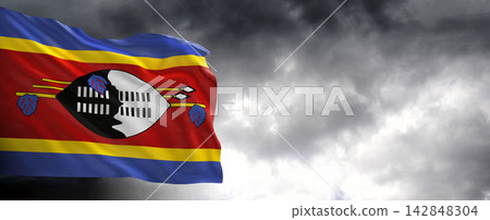Eswatini (Swaziland) Flag Waving Against Dark Cloudy Sky Eswatini (Swaziland) Flag Waving Against Dark Cloudy Sky 142848304