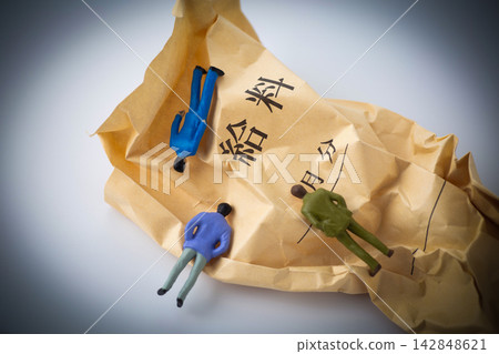白色背景上,一個皺巴巴的工資信封和一個倒下的商人。 白色背景上,一個皺巴巴的工資信封和一個倒下的商人。 142848621