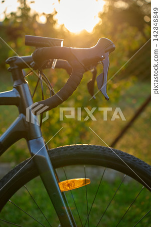 Close-up of a gravel bike with front wheel, drop handlebars at sunset Close-up of a gravel bike with front wheel, drop handlebars at sunset 142848849
