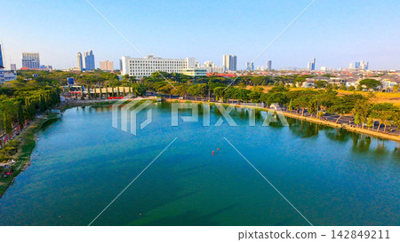 Panoramic view of Danau UNESA lake surrounded by green trees and city skyline in Surabaya East Java. Panoramic view of Danau UNESA lake surrounded by green trees and city skyline in Surabaya East Java. 142849211