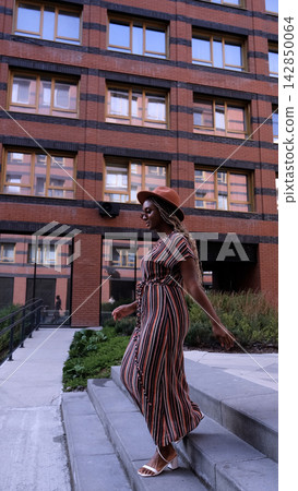 Young woman resting and relaxing while walking on city street in new eco-friendly residential complex. Relaxation and stress-free concept. 142850064
