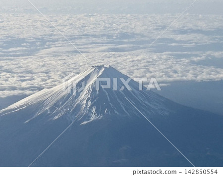 A view of snow-capped Mount Fuji and a vast sea of clouds from the window of an airplane. A view of snow-capped Mount Fuji and a vast sea of clouds from the window of an airplane. 142850554