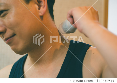 一位四十多歲的男子將止汗滾珠塗抹在後頸上。 一位四十多歲的男子將止汗滾珠塗抹在後頸上。 142850645