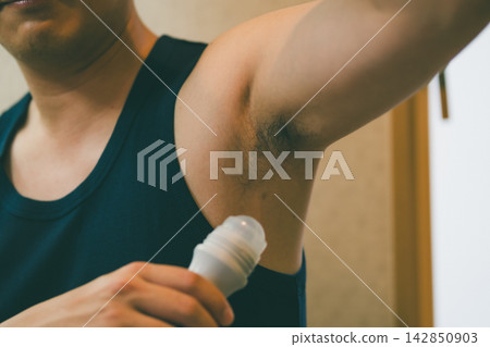 一位四十多歲的男子正在腋下塗抹滾珠式除臭劑。 142850903
