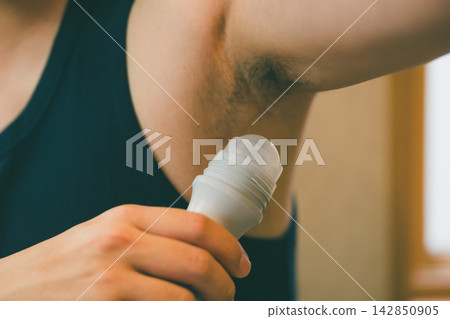 一名男子正在往腋下塗抹止汗劑。 一名男子正在往腋下塗抹止汗劑。 142850905