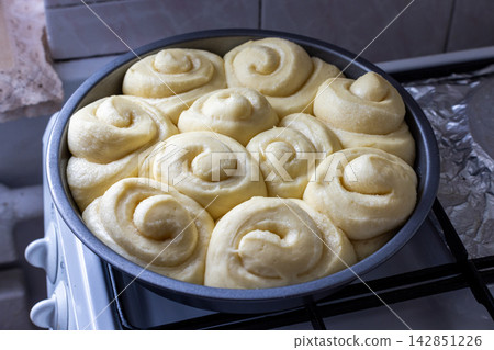 Raw Dough Rolls in Baking Pan on Stovetop 142851226