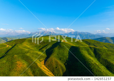 Aerial View of Green Rolling Hills and Snow-Capped Mountains Aerial View of Green Rolling Hills and Snow-Capped Mountains 142851237