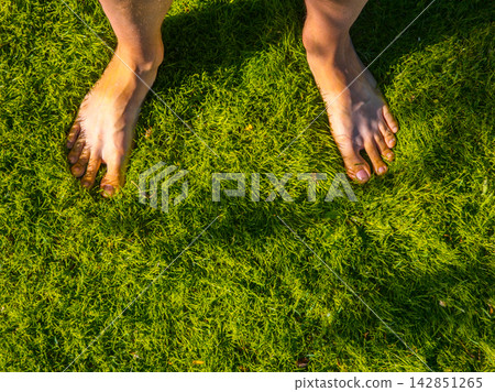 Bare Feet on Lush Green Grass Under Sunlight 142851265