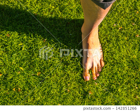 Bare Foot Stepping on Green Grass in Bright Sunlight Bare Foot Stepping on Green Grass in Bright Sunlight 142851266