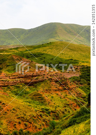Rolling Green Hills and Eroded Red Earth Landscape in Kyrgyzstan Rolling Green Hills and Eroded Red Earth Landscape in Kyrgyzstan 142851355