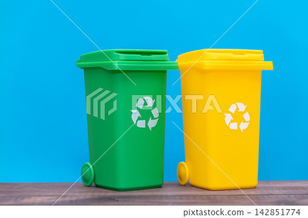 Green and yellow recycling bins standing on a blue background Green and yellow recycling bins standing on a blue background 142851774