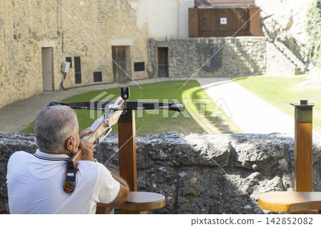 A man is practicing with a crossbow in a courtyard in San Marino A man is practicing with a crossbow in a courtyard in San Marino 142852082