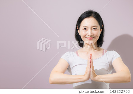 一位日本中年女性擺出姿勢,看著鏡頭,放鬆身心。 一位日本中年女性擺出姿勢,看著鏡頭,放鬆身心。 142852793