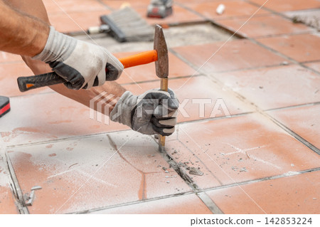Floor renovation involving manual tile breaking, mortar removal, dust and construction debris from the damaged surface. Floor renovation involving manual tile breaking, mortar removal, dust and construction debris from the damaged surface. 142853224