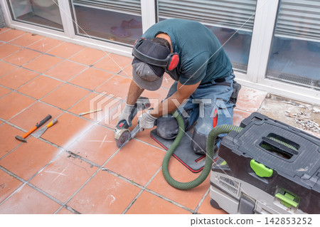 Worker grinding terracotta tiles during floor renovation on outdoor patio Worker grinding terracotta tiles during floor renovation on outdoor patio 142853252