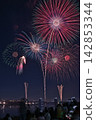 Fireworks soaring into the night sky; fireworks blooming in the summer night sky; fireworks blooming in the night sky; a fireworks display shining brightly; people watching the fireworks. 142853344