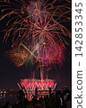 Fireworks soaring into the night sky; fireworks blooming in the summer night sky; fireworks blooming in the night sky; a fireworks display shining brightly; people watching the fireworks. 142853345