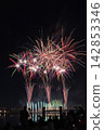 Fireworks soaring into the night sky; fireworks blooming in the summer night sky; fireworks blooming in the night sky; a fireworks display shining brightly; people watching the fireworks. 142853346
