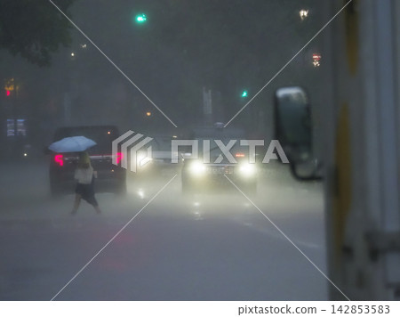Pedestrians crossing a crosswalk on a rainy day Pedestrians crossing a crosswalk on a rainy day 142853583