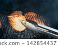 Grilled bread slices over hot coals with tongs. Rustic BBQ background Grilled bread slices over hot coals with tongs. Rustic BBQ background 142854437