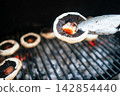 Grilled mushrooms over hot coals with tongs Grilled mushrooms over hot coals with tongs 142854440
