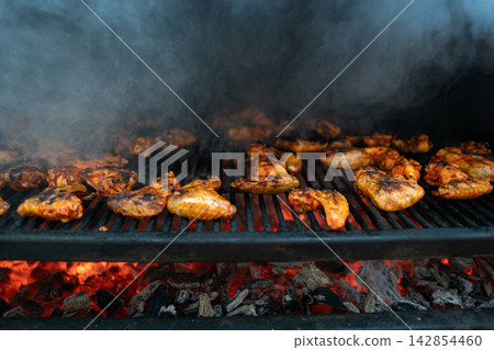 Delicious BBQ Chicken Wings Cooking on an Outdoor Charcoal Grill Delicious BBQ Chicken Wings Cooking on an Outdoor Charcoal Grill 142854460
