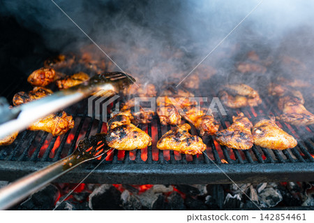 Grilled chicken pieces over hot charcoal with smoky flavor. Outdoor BBQ Grilled chicken pieces over hot charcoal with smoky flavor. Outdoor BBQ 142854461
