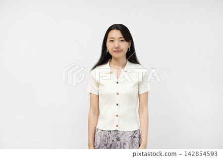 一位年輕的日本女子站在白牆前看著鏡頭。 142854593