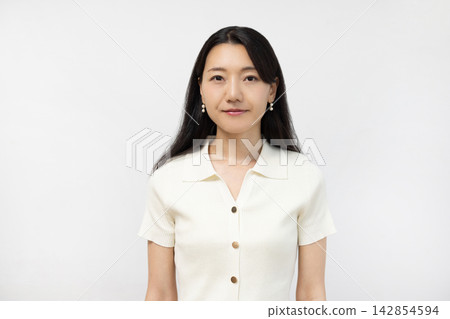 一位年輕的日本女子站在白牆前看著鏡頭。 142854594